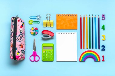 Okul ve ofis malzemelerinden çerçeve ataçlar, kalemler, hesap makinesi, keskinleştirici, not defteri, mavi arkaplanda izole edilmiş zımba. Üst görünüm okula, eğitim kavramına geri dön. Boşluğu kopyala.