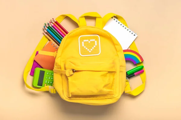 Back to school, education concept Yellow backpack with school supplies - notebook, pens, eraser rainbow, numbers isolated on beige background Top view Copy space Flat lay composition.