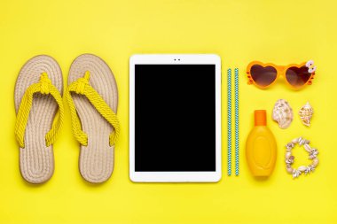 Yüzme aksesuarları - modaya uygun plaj fiskesi, portakal rengi gözlük, deniz kabuğu, beyaz tablet, sarı arka planda güneş kremi Üst Manzara Yazı, seyahat, parti, tatil konsepti.