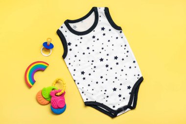 Yeni doğan bebekler için yıldızlı güzel elbiseler, sarı arka planda izole edilmiş pamuk kumaş kopyalama alanı, çocukluk, annelik, moda tekstili ve yeni doğan Top view.