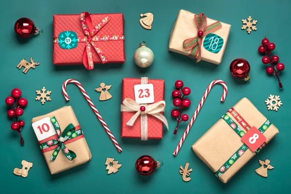 El yapımı kırmızı, yeşil hediye kutuları. Kurdeleler, kar taneleri ve numaralarla dekore edilmiş, Noel süslemeleri ve yeşil masa süsleri. Xmas takvimine yeni bir takvim konsepti..