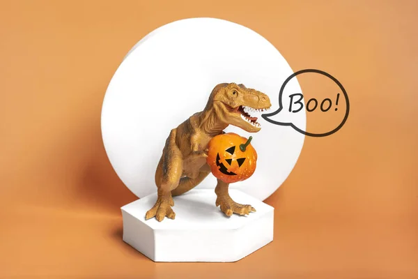 Toy Dinosaur Tyrannosaurus Holding Pumpkin Its Paws White Podium Isolated — 스톡 사진