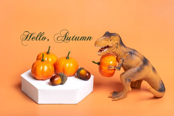 Toy Dinosaur Tyrannosaurus Holding Pumpkin Its Paws White Podium Isolated — Foto de Stock