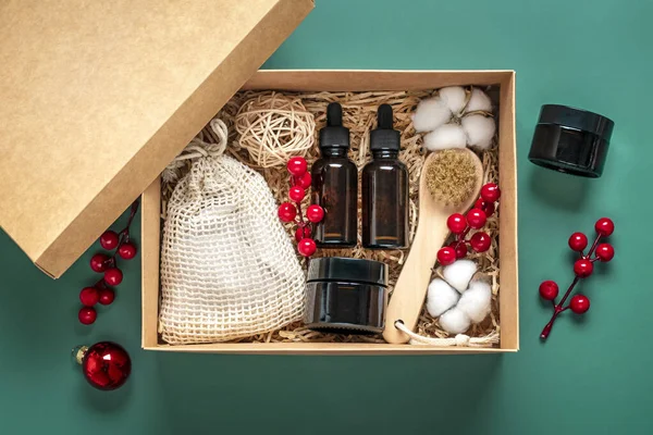 Set for care box Eco-friendly cosmetics Oil and cream bottles, brush for washing, cotton pads on green background Gift for girlfriend, mother to celebrate Christmas concept Top view Flat lay.