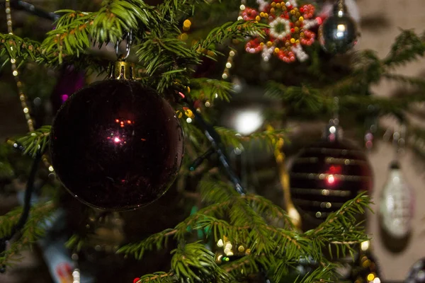 Yeşil dalların ve ışıkların arka planında Noel oyuncakları — Stok fotoğraf
