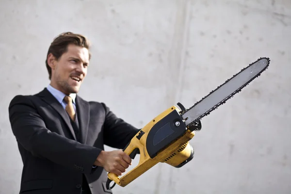 Angry businessman wielding a chainsaw. — Stock Photo, Image