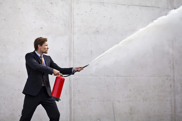 Focused businessman using a fire extinguisher — Stock Photo, Image