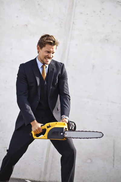 Crazy businessman with a chainsaw — Stock Photo, Image