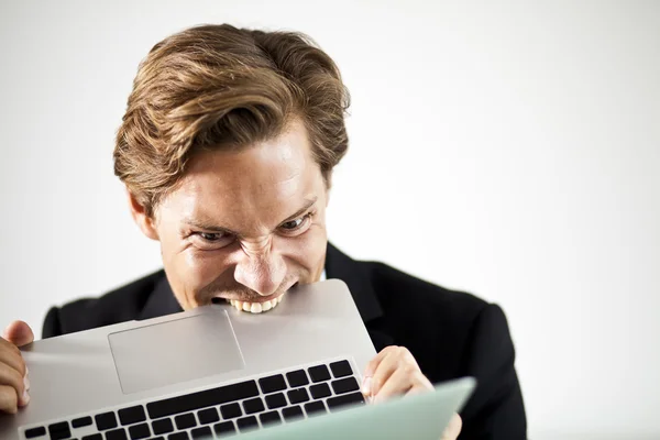 Man biting a laptop in frustration — Stock Photo, Image