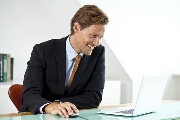 Sorridente bonito empresário usando laptop no escritório — Fotografia de Stock