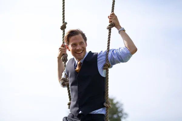 Hombre de negocios sonriente balanceándose en cuerdas —  Fotos de Stock