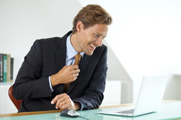 Biznesmen uśmiechający się siedząc przy biurku — Zdjęcie stockowe