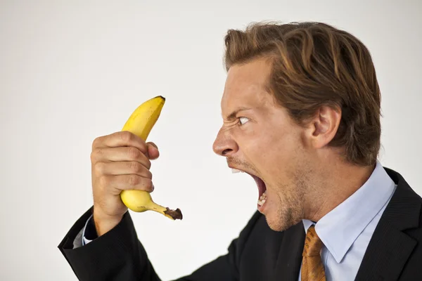 Wütender Geschäftsmann brüllt Banane an Stockbild