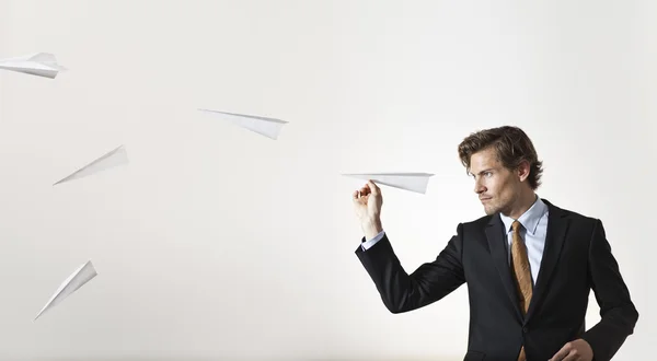 Empresario lanzando aviones de papel al blanco Imagen de archivo