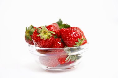 Beyaz arka planda izole edilmiş cam kasedeki çilekler.