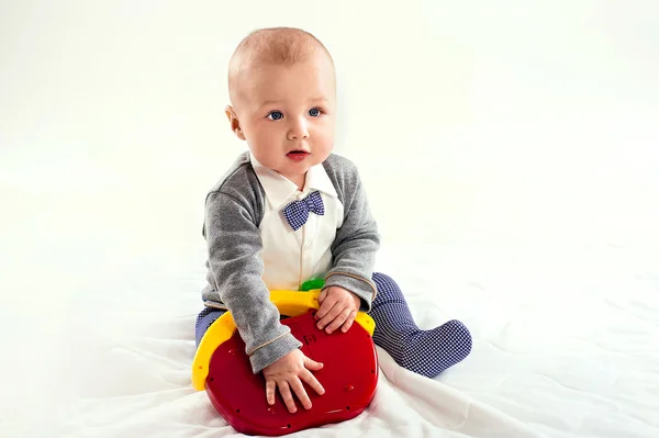 O menino pequeno brinca com um brinquedo vermelho — Fotografia de Stock