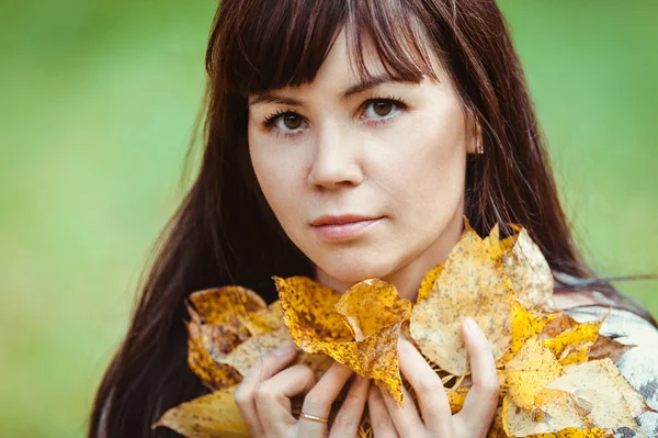Porträt einer Frau mit gelben Blättern in einem herbstlichen Park — Stockfoto
