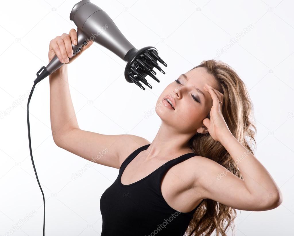 girl dries long hair with hairdryer