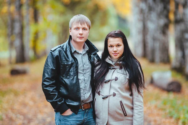 Pregnant woman and her husband walking in the autumn park — Stock Photo, Image