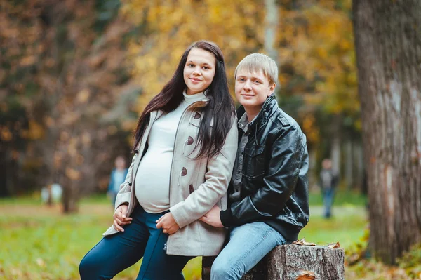 年轻怀孕夫妇在秋天公园散步 — 图库照片
