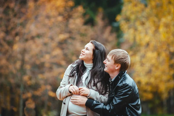 若い夫婦妊娠秋の公園でウォーキング — ストック写真