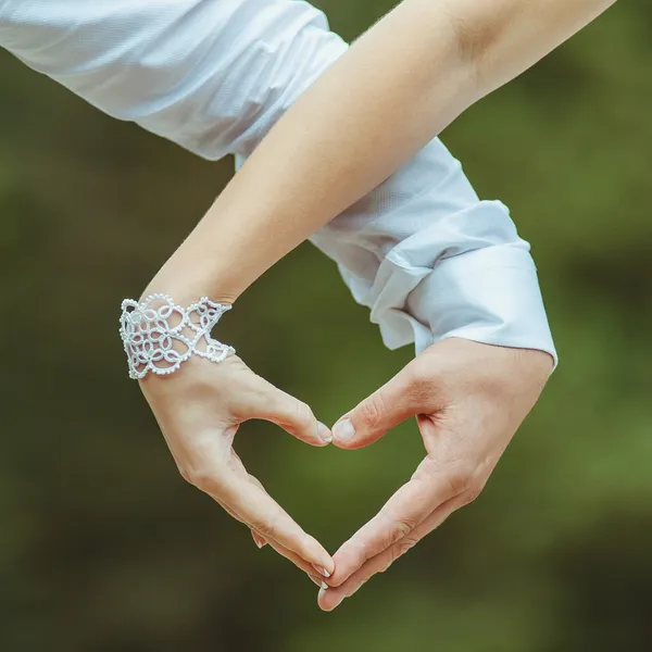 Mann und Frau halten sich an den Händen und machen Liebesherz — Stockfoto