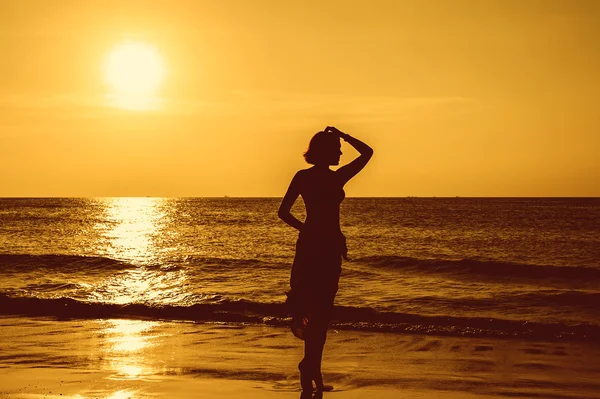 Silueta mujer joven en la playa al atardecer. — Foto de Stock