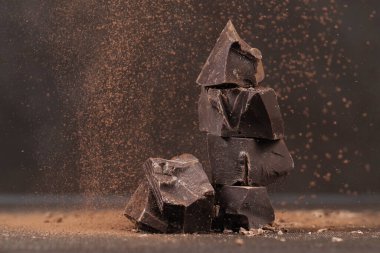 Masanın üzerinde kırılmış siyah çikolata ve kakao tozu