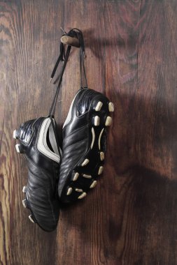 Ahşap duvarda asılı bir çift futbol ayakkabısı. Futbol kariyerinin sonu.