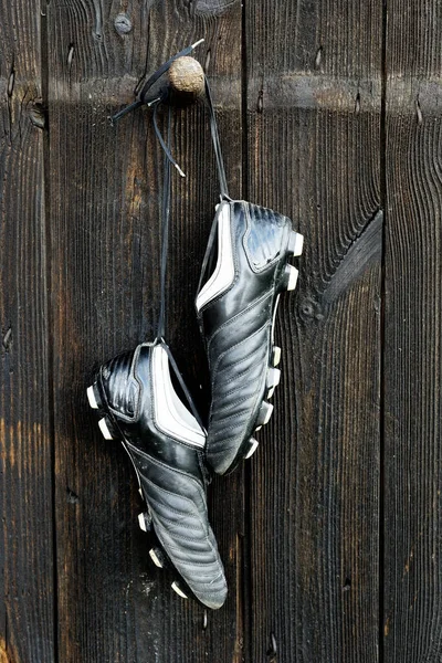 A pair of soccer boots hanging on a wooden wall. The end of the football career