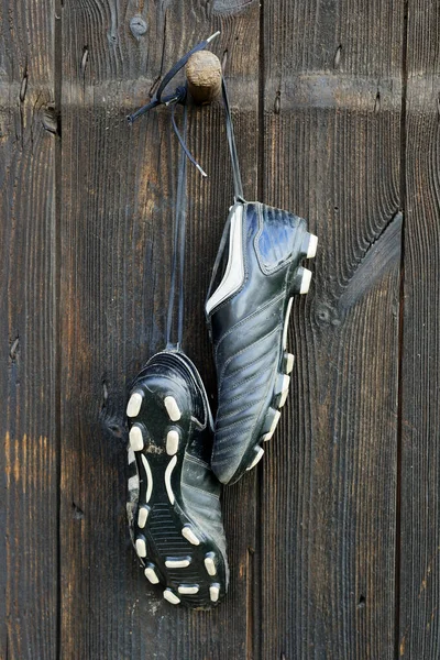 A pair of soccer boots hanging on a wooden wall. The end of the football career