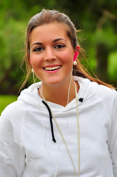 Giovane donna sorridente e indossando auricolari — Foto Stock