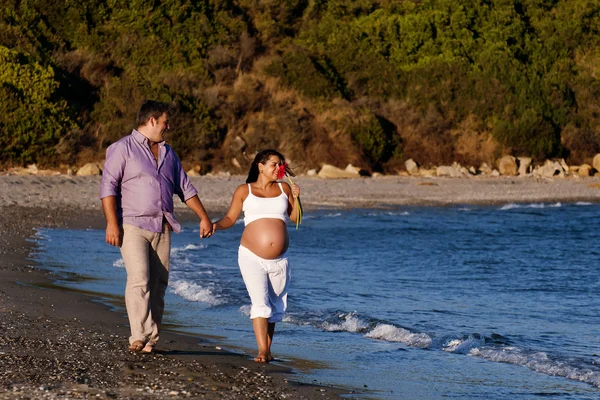 Par som väntar barn promenerar på stranden Royaltyfria Stockbilder