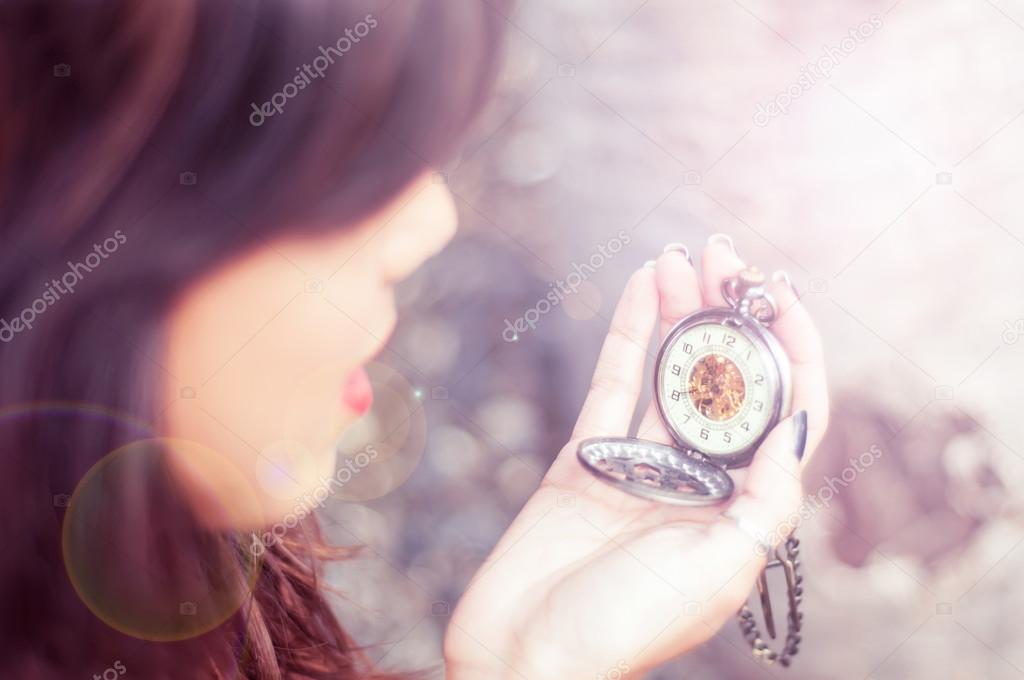Young woman checking time on a pocket watch