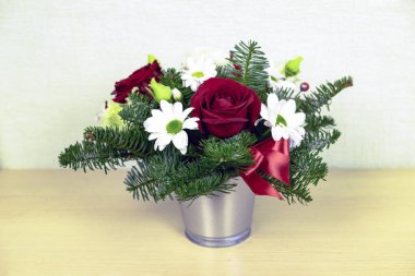 Kış buketi kırmızı güller, beyaz kasımpatılar ve metal kovada ladin dalları.