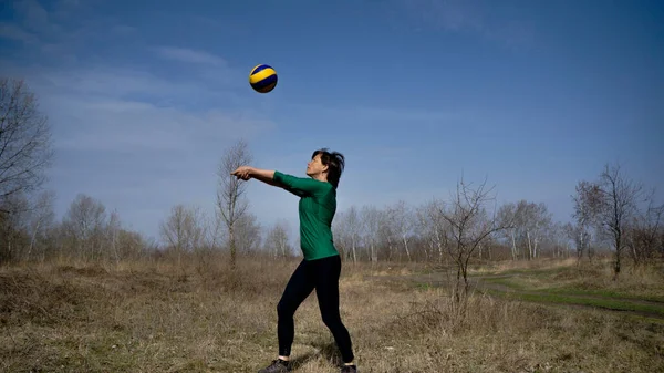 Güneşli bir günde orta yaşlı bir kadın dışarıda voleybol oynuyor. Spor. aktif yaşam tarzı. Fitness. Voleybol