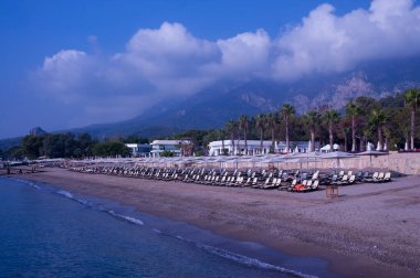 Deniz kıyısında. Hava açık. Yaz. Dinlen. Seyahatler. kumsal, palmiye ağaçları ve dağlar