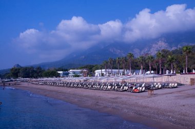 Deniz kıyısında. Hava açık. Yaz. Dinlen. Seyahatler. kumsal, palmiye ağaçları ve dağlar