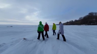 Bir grup insan karla kaplı ve donmuş bir denizde yürüyor..