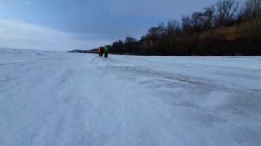 Bir grup insan karla kaplı ve donmuş bir denizde yürüyor..
