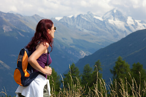 Woman wearing a backpack hiking the Alps.