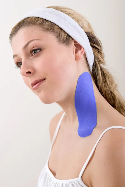 Mujer con una cinta de kinesiología azul en el cuello . — Foto de Stock