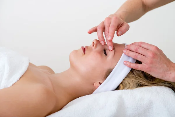 Masseuse massaging a woman eyebrow area. — Stock Photo, Image