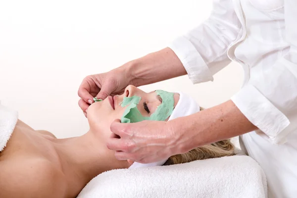 Kosmetikerin beim Abschälen einer grünen Thalasso-Gesichtsmaske. — Stockfoto