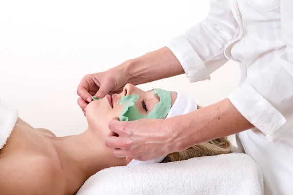 Esteticista peeling off un verde talasso belleza facial máscara . — Foto de Stock