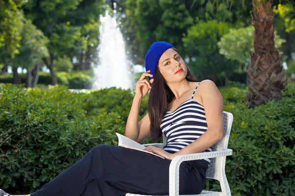 Hermosa estudiante femenina está leyendo un libro al aire libre . — Foto de Stock