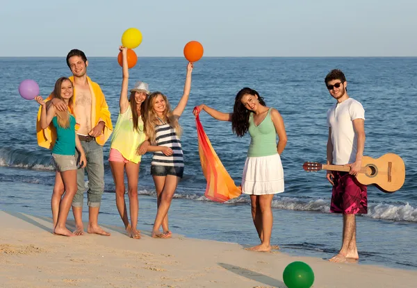 Grupp av unga människor njuter av beach party med gitarr och ballo — Stockfoto