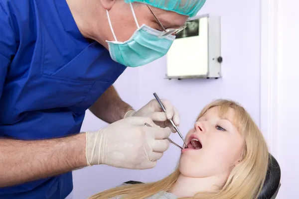 Dental-chirurg onderzoeken de tanden van een vrouw. — Stockfoto