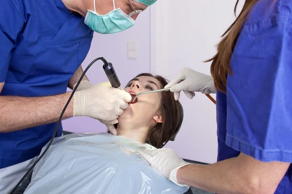 Tandarts en zijn assistent werkzaam op een patiënt. — Stockfoto