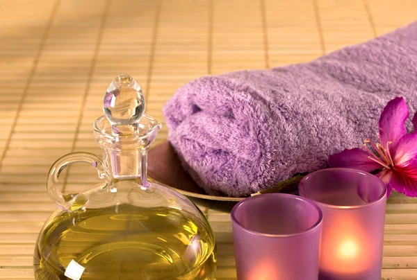 Essential oil, candles, towel and purple flowers. — Stock Photo, Image